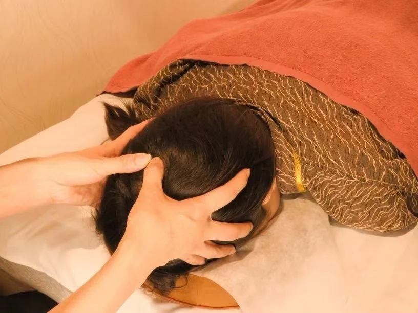 タオルをかけた施術ベッドで背中を整える施術